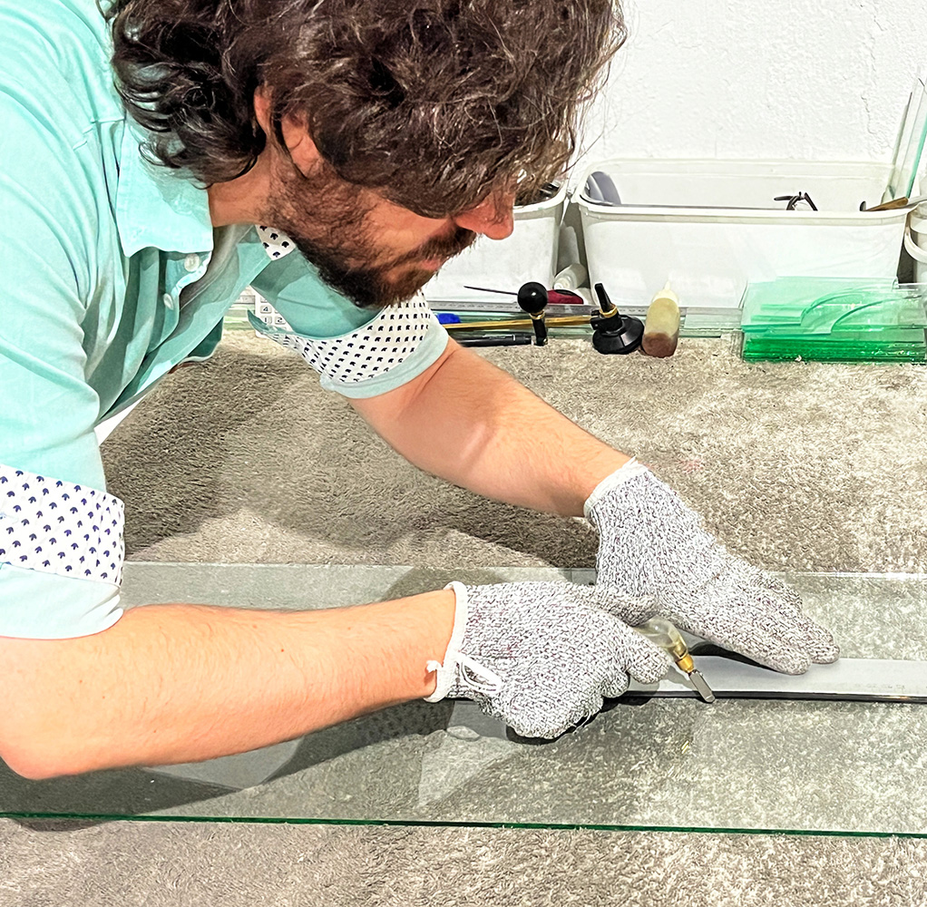 A Fanglasstic artisan carefully scoring a glass sheet.